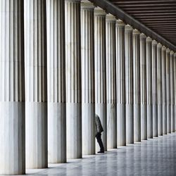 Man standing by architectural columns of building