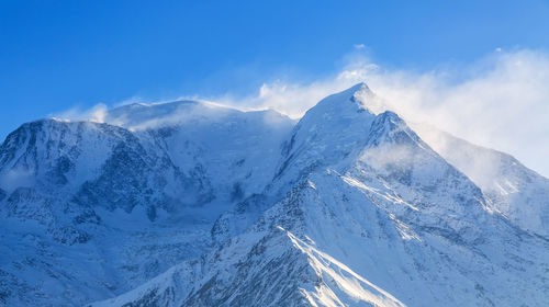 Scenic view of snowcapped mountains against blue sky