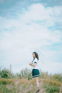 Side view of woman standing on field against sky