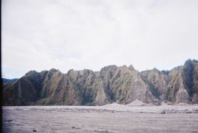 Scenic view of land and mountains against sky