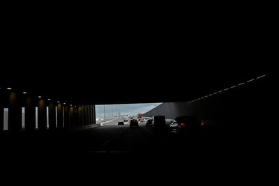 Vehicles on road in illuminated tunnel