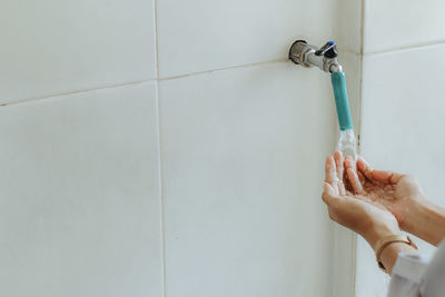 Midsection of person with arms raised against wall at home