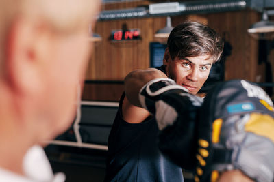 Portrait of man boxing while standing in gym