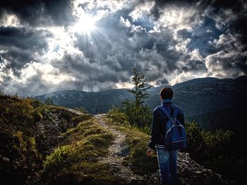 Rear view of man standing on mountain against sky