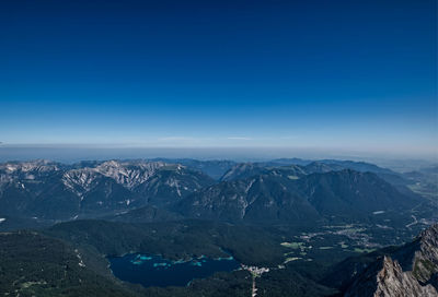 Aerial view of snowcapped mountain against blue sky