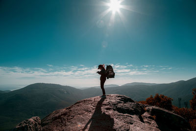 Low angle view of man standing on mountain against sky