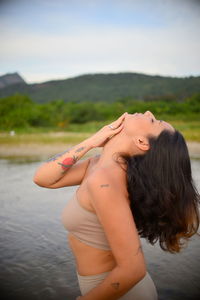 Side view of woman in lingerie exercising by lake