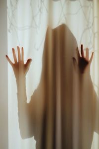 Person standing behind curtain at home