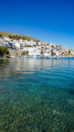 Sea by buildings against clear blue sky