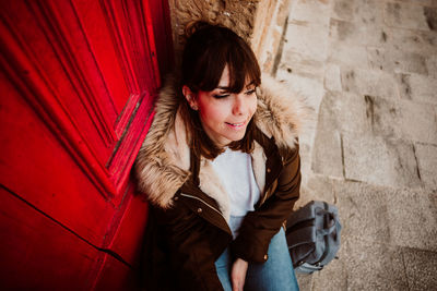 High angle view of woman with backpack sitting by door