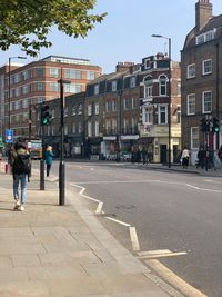 People walking on sidewalk by buildings in city