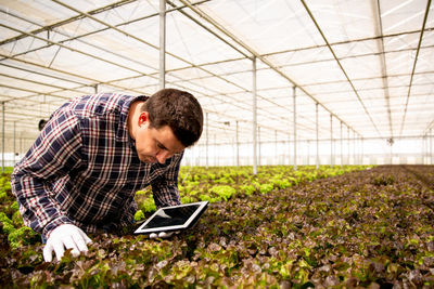 Side view of man using laptop while standing on field