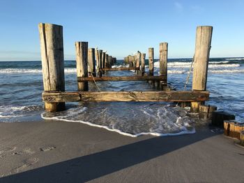 Wooden posts on beach against sky