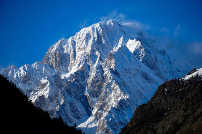 Scenic view of snowcapped mountains against blue sky