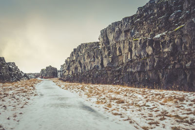 Road amidst rocks against sky during winter