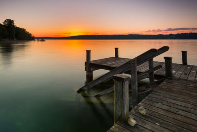 Wooden pier over lake against sky during sunset