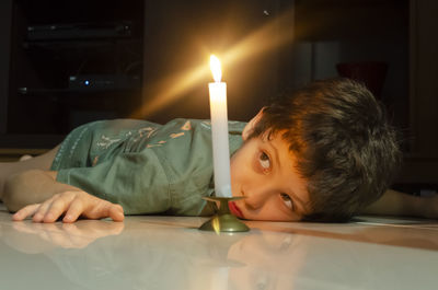 Child looking at a lit candle lying on the floor of the house. salvador, bahia, brazil.