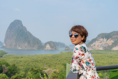 Man wearing sunglasses standing by mountain against sky