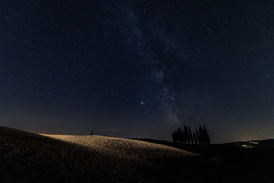 Scenic view of field against sky at night, milky way in tuscany