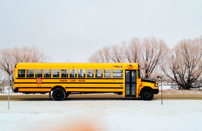 Yellow vintage car on snow against clear sky