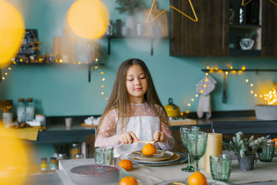 Child girl is sitting at a festive table set for christmas and smiling