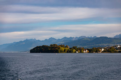 Scenic view of sea by mountains against sky