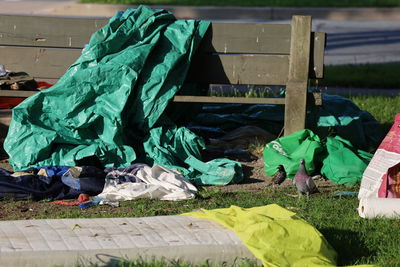 Stack of garbage can by bench, homelessness.