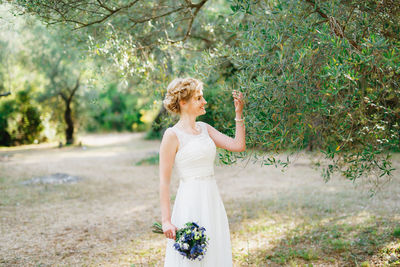 Young woman standing by tree on field