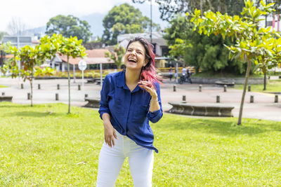 Full length of a smiling young woman standing outdoors