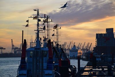 Sailboats moored at harbor against sky during sunset