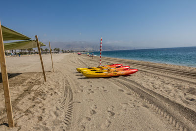 Deck chairs on beach against clear sky
