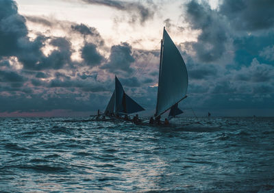 Sailboat sailing in sea against sky during sunset