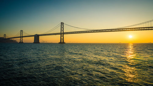 Bridge over sea against sky during sunset