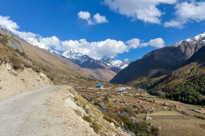 Scenic view of road by mountains against sky