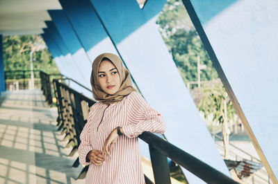 Thoughtful woman wearing hijab while standing by railing