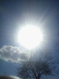 Low angle view of sun shining through clouds