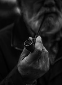 Midsection of senior man holding smoking pipe