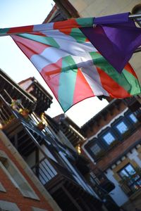 Low angle view of flags hanging against buildings in city