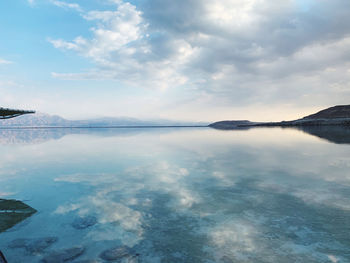 Scenic view of sea by mountains against sky