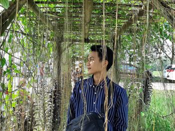 Portrait of smiling young woman standing against plants
