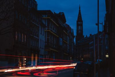 Light trails on city street amidst buildings at night