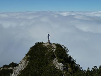 Low angle view of man standing on rock against sky