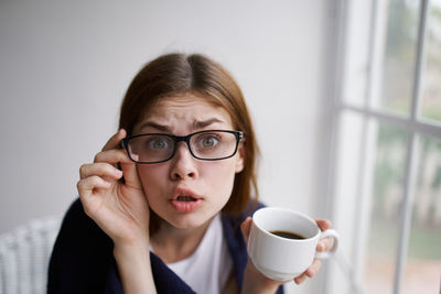 Portrait of woman making face drinking coffee