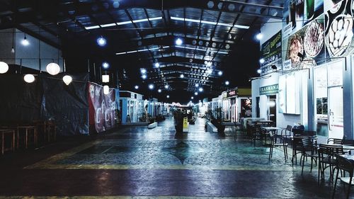 Empty illuminated street amidst buildings in city at night