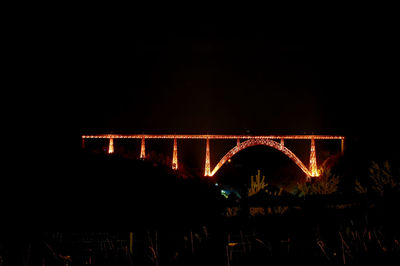Low angle view of illuminated bridge against clear sky at night