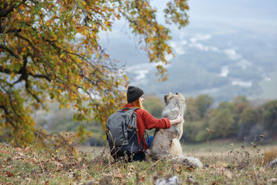 Rear view of man sitting on field during autumn