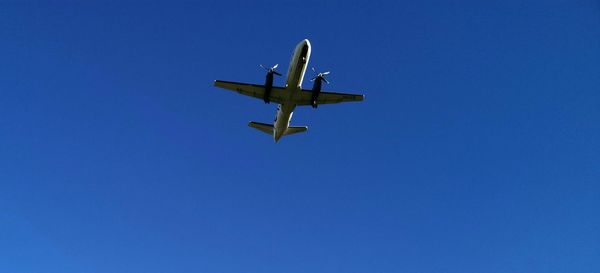 Low angle view of airplane against clear blue sky