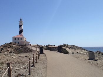 Lighthouse on beach by sea against clear sky minorca