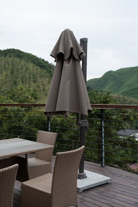 Chairs and table by swimming pool against sky