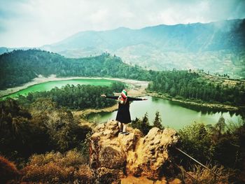 Man standing by lake against mountains